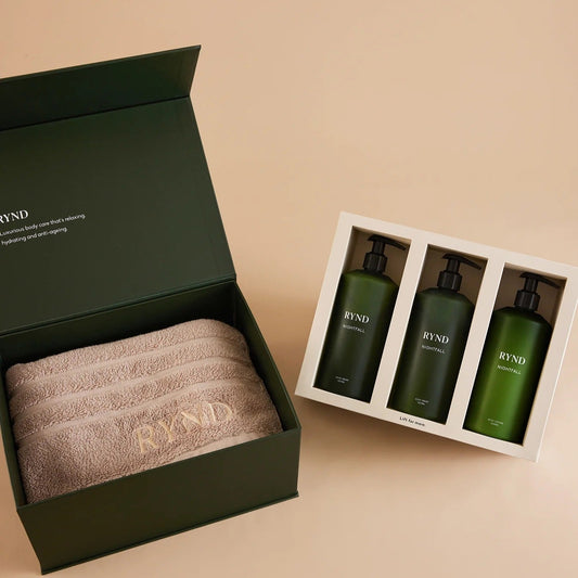Green gift set with towels and bottles labeled 'RNYD' on a beige background